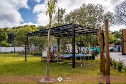 Área de recreação coberta com cama elástica e carroça decorativa no gramado