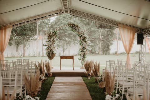 Cerimônia de casamento ao ar livre com arco de flores e passarela de madeira, ideal para casamento evangélico ou tradicional