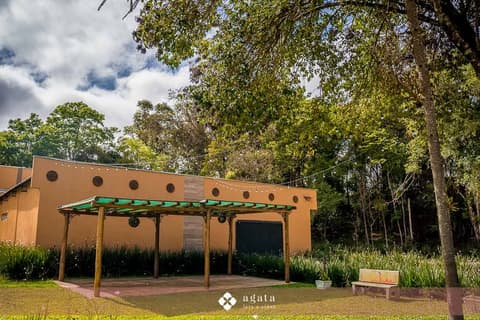 Pergolado com deck de madeira em frente à fachada amarela, cenário para cerimônias e fotos