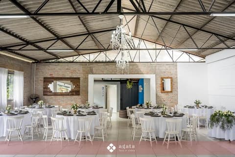 Salão de festas com lustres de cristal e mesas redondas decoradas para casamento