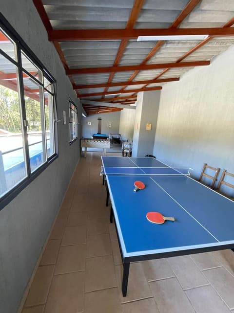 Salão de jogos com mesa de ping-pong, pebolim e sinuca